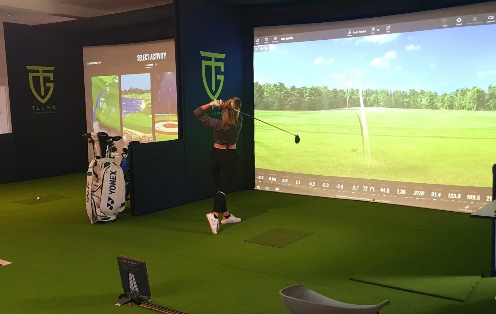 A golfer practising in a TrackMan simulator bay at TeeGo Battersea